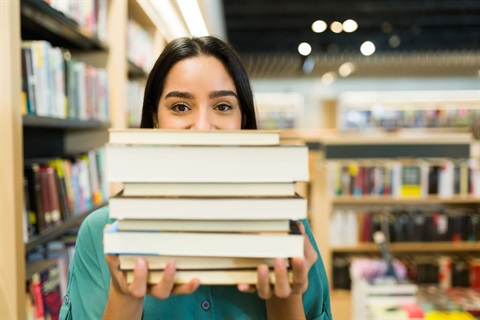 An excited woman holding a stack of books